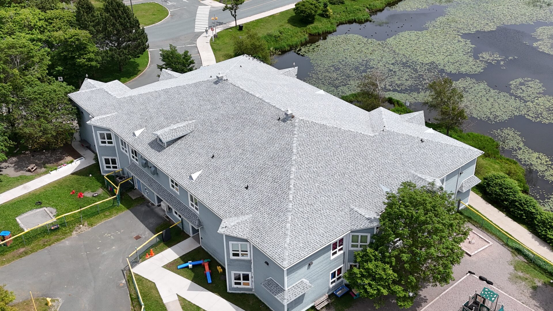 Aerial view of a gray multi-story building with a shingled roof