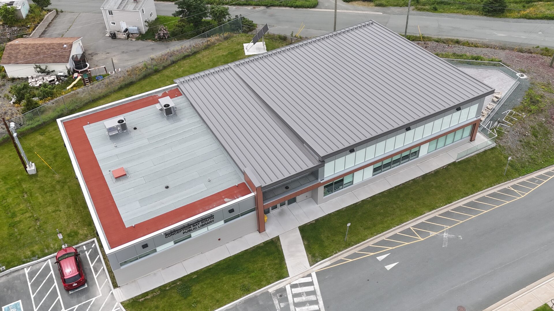The building has a unique design, with a metal roof and a red tiled roof The building has a unique design, with a metal roof and a red tiled roof